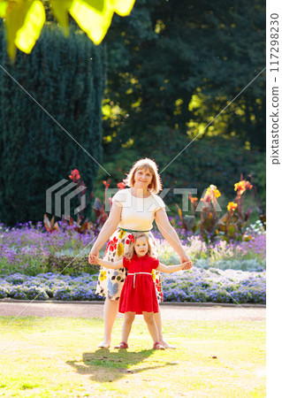 Young woman playing with little girl in a park Young woman playing with little girl in a park 117298230