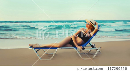 Summer vacation, happy relaxing young woman lying on deckchair on the beach on sea background Summer vacation, happy relaxing young woman lying on deckchair on the beach on sea background 117299336