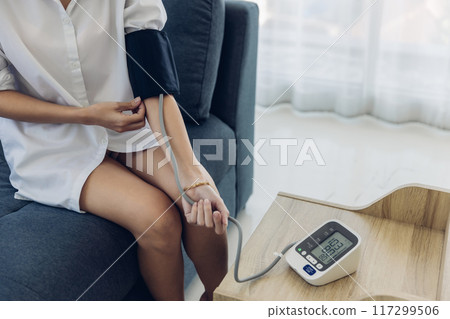 Woman measuring blood pressure by using digital sphygmomanometer at home Woman measuring blood pressure by using digital sphygmomanometer at home 117299506