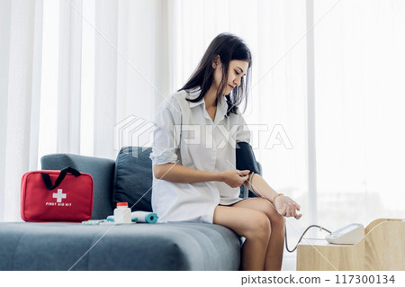 Woman measuring blood pressure by using digital sphygmomanometer at home Woman measuring blood pressure by using digital sphygmomanometer at home 117300134