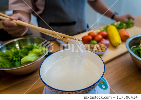 Chef at the kitchen preparing spicy glass noodle salad 117300414