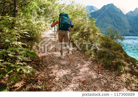 A Hiker Embarking on an Exciting Trekking Journey Through a Beautiful Scenic Nature Trail 117300889
