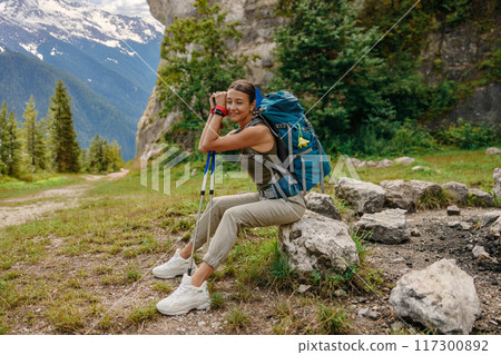 A Relaxing Hiker Enjoys the Scenic Beauty of a Majestic Mountain Landscape with a Backpack 117300892