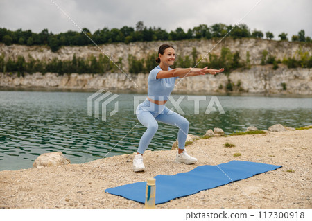 A woman engaging in exercise outdoors close to the water, enjoying the fresh air and nature A woman engaging in exercise outdoors close to the water, enjoying the fresh air and nature 117300918