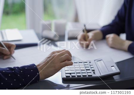 Two unrecognizable accountants or auditors reviewing financial data in office. Professionals analyzing paper reports and using calculator, close up. Audit concept Two unrecognizable accountants or auditors reviewing financial data in office. Professionals analyzing paper reports and using calculator, close up. Audit concept 117301193