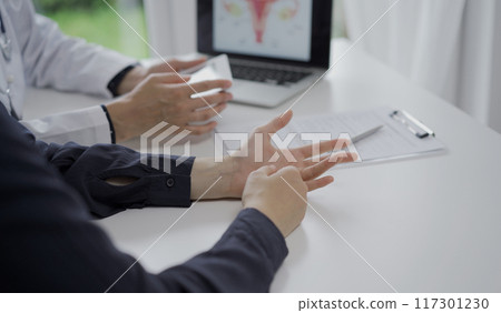Doctor and a patient in clinic. The female physician is using tablet computer for filling up medication history record form, close up of woman hands. Medicine and science Doctor and a patient in clinic. The female physician is using tablet computer for filling up medication history record form, close up of woman hands. Medicine and science 117301230