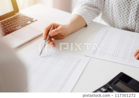 Accountant using a calculator and laptop computer for counting taxes with a client or a colleague at white desk in office. Teamwork in business audit and finance Accountant using a calculator and laptop computer for counting taxes with a client or a colleague at white desk in office. Teamwork in business audit and finance 117301272