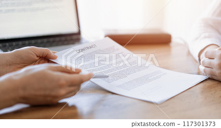 Businesswoman lawyer pointing into contract special points admitting something for colleague or client at the wooden desk in office. Business people teamwork and partnership, meeting concept 117301373