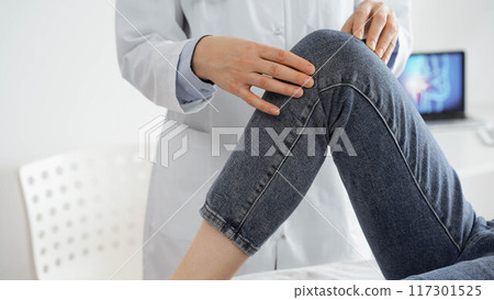 Doctor and patient are at the medical inspection in clinic. Orthopedic examines the knee of a young woman. Medicine concept 117301525