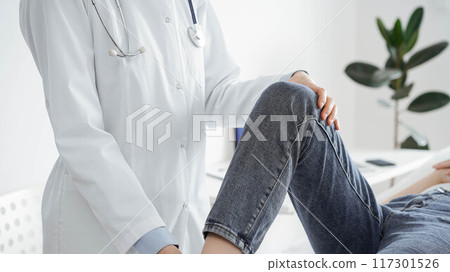 Doctor and patient are at the medical inspection in clinic. Orthopedic examines the knee of a young woman. Medicine concept 117301526