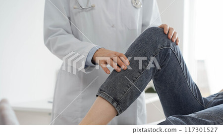 Doctor and patient are at the medical inspection in clinic. Orthopedic examines the knee of a young woman. Medicine concept Doctor and patient are at the medical inspection in clinic. Orthopedic examines the knee of a young woman. Medicine concept 117301527