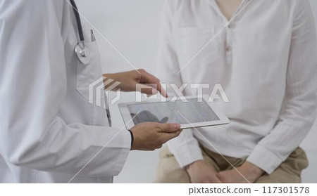 Doctor and a patient. The female physician is pointing into tablet computer besides a young woman during a consultation in the clinic. Medicine concept Doctor and a patient. The female physician is pointing into tablet computer besides a young woman during a consultation in the clinic. Medicine concept 117301578