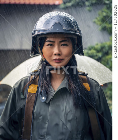 Stock image of a woman wearing a helmet standing in front of rubble 117302628
