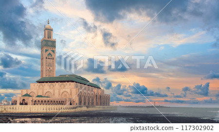 Hassan II Mosque during sunset, built on the Atlantic Ocean, showcasing impressive architecture and intricate details reflecting rich cultural heritage. 117302902