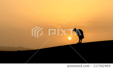 Silhouette of unidentified muslim Berber man praying on sand dunes at beautiful sunset in Sahara Desert, Morocco Silhouette of unidentified muslim Berber man praying on sand dunes at beautiful sunset in Sahara Desert, Morocco 117302909