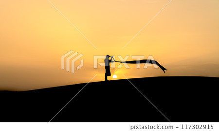 Silhouette of unidentified Berber man in his long robe and turban billow in the wind on sand dunes at beautiful sunset in Sahara Desert, Morocco Silhouette of unidentified Berber man in his long robe and turban billow in the wind on sand dunes at beautiful sunset in Sahara Desert, Morocco 117302915