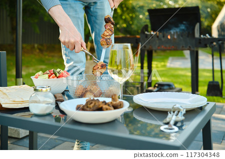 Unrecognizable man removes kebab from skewer 117304348