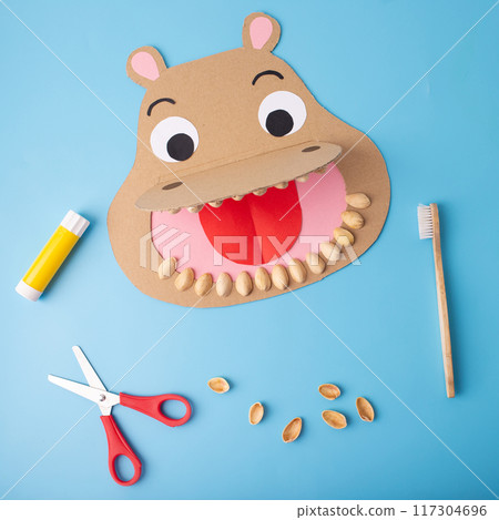 DIY recycling craft concept paper cut shaped like a hippo with a toothbrush puppet, tutorial for kids' dental health education 117304696