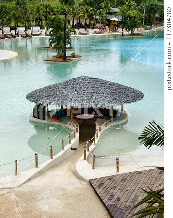 A traditional thatched hut is located within a swimming pool 117304780