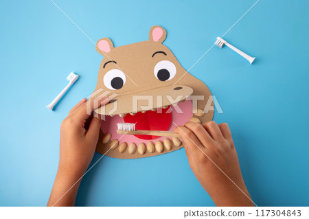a paper cut shaped like a hippo with a toothbrush, DIY, recycling craft concept, teeth and dental health for kids 117304843