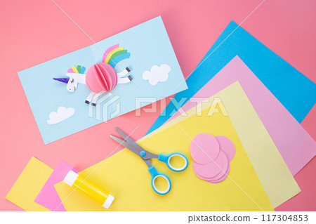 Whimsical paper cutout of a unicorn soaring through the sky, crafted in pastel tones and displayed as a complete card in an overhead view. Great for fantasy-themed artwork and creative projects Whimsical paper cutout of a unicorn soaring through the sky, crafted in pastel tones and displayed as a complete card in an overhead view. Great for fantasy-themed artwork and creative projects 117304853