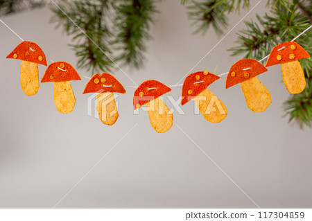 a string of mushrooms made of dry tangerine peel hanging, decorations, front view, craft for kids, 117304859