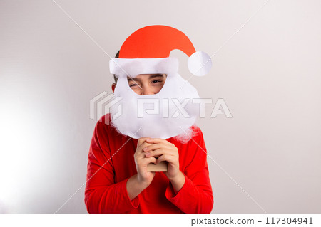 a boy wearing a paper craft santa hat and beard, disguise New Year mask, DIY, ideas for winter kids activity, recycled paper a boy wearing a paper craft santa hat and beard, disguise New Year mask, DIY, ideas for winter kids activity, recycled paper 117304941