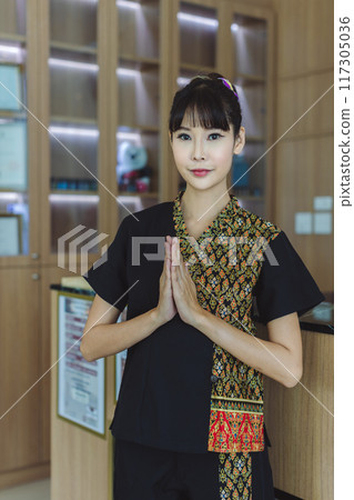 Woman pray respect or sawasdee. Thai women welcome with traditional Thai suit in shop Woman pray respect or sawasdee. Thai women welcome with traditional Thai suit in shop 117305036