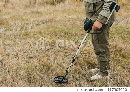 Man with electronic metal detector device working on outdoors. Man with electronic metal detector device working on outdoors. 117305620