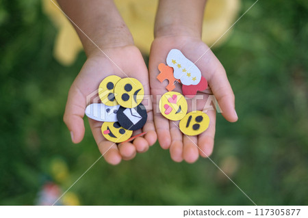 A variety of paper emojis and a set of icons in the hands of a child 117305877
