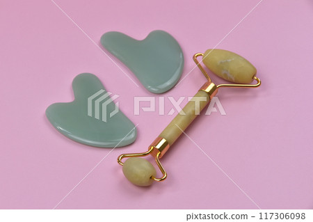 Gua Sha face tool, green stone massage roller on a dark background with copy space, spa background with place for text, skin care 117306098