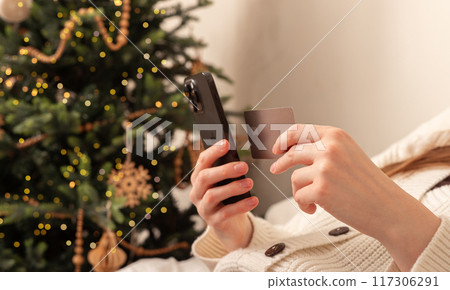 Lodz Poland July 20 2024, hands holding and using mobile phone, iphone smartphone on Christmas 117306291