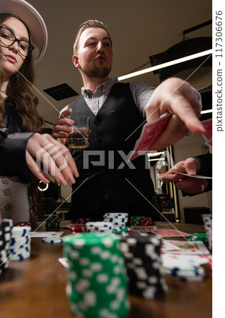 A team rejoices at a poker win against the background of glasses of whiskey. A casino player throws gambling chips on the table. A team rejoices at a poker win against the background of glasses of whiskey. A casino player throws gambling chips on the table. 117306676