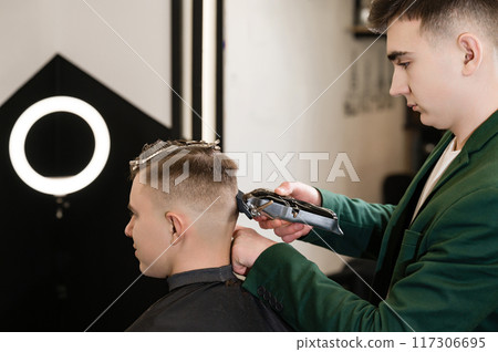 Haircut and alignment of the head contour with a hair clipper trimmer. Short haircut in the barbershop. 117306695