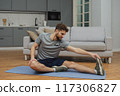 Training to become the best. Beautiful young man in sports clothing exercising at home. 117306827