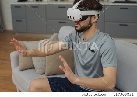 Training to become the best. Beautiful young man in sports clothing exercising at home. 117306831