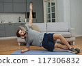 Training to become the best. Beautiful young man in sports clothing exercising at home. 117306832