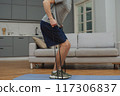 Training to become the best. Beautiful young man in sports clothing exercising at home. 117306837
