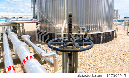 Handle of a manual vertical crane on a pipe coming out of a large tank Handle of a manual vertical crane on a pipe coming out of a large tank 117306945