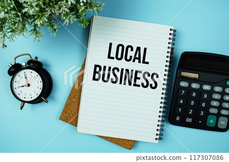 Local Business text written on paper card with calculator and alarm clock on blue background 117307086