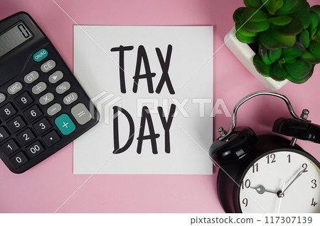 Tax Day text with calculator and alarm clock on pink background 117307139
