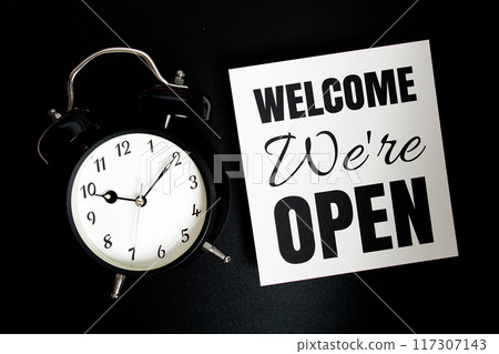 Welcome We're OPEN text with alarm clock on black background Welcome We're OPEN text with alarm clock on black background 117307143