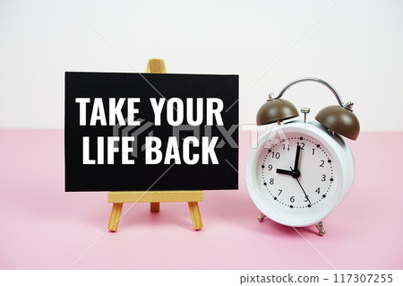 Take your life back text written on paper card with easel standing and alarm clock on pink background 117307255
