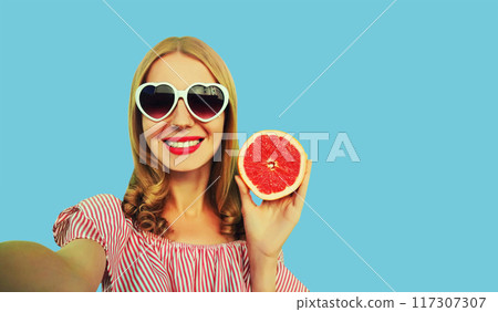 Summer portrait of happy smiling woman taking selfie with phone, fruit in heart shaped glasses 117307307