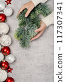 Red and white Christmas baubles in a box flat lay. Merry Christmas and Happy New Year seasons greetings card. Copy space. Festive border hands holding fur tree branch 117307341