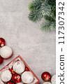 Red and white Christmas baubles in a box flat lay. Merry Christmas and Happy New Year seasons greetings card. Copy space. Festive border with fur tree branch 117307342