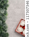 Red and white Christmas baubles in a box flat lay. Merry Christmas and Happy New Year seasons greetings card. Copy space. Festive border with fur tree branch 117307346