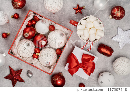 Red and white Christmas baubles in a box flat lay. Merry Christmas and Happy New Year seasons greetings card. Copy space. Festive full frame 117307348