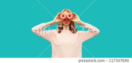 Portrait of happy funny woman covering her eyes looking through donuts as binoculars having fun 117307690