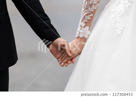 Bride and groom with bands holding hands and touching during their wedding ceremony Bride and groom with bands holding hands and touching during their wedding ceremony 117308453